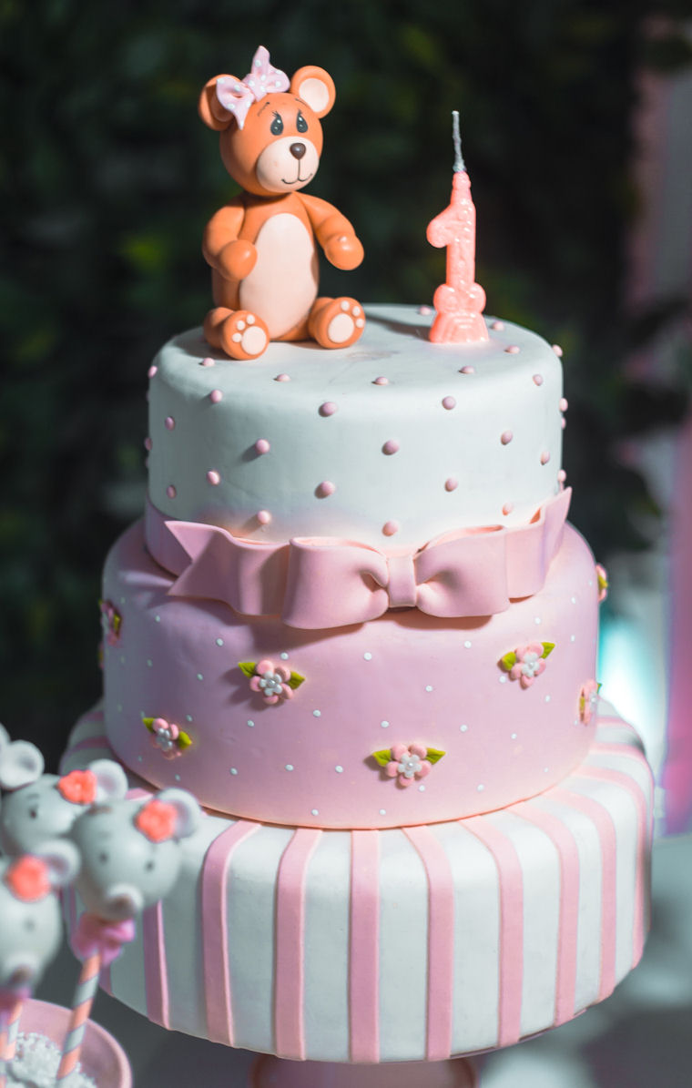 Three tier birthday cake
                    with pink, white and blue icing, the numeral 1 and a
                    teddy bear on the top