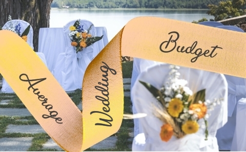 Apricot Ribbon reading
                      Average Wedding Budget over a background of white
                      covered chairs decorated with multicoloured
                      flowers with a river in the background