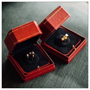 Two red ring boxes open
                      to show wedding rings on a charcoal background