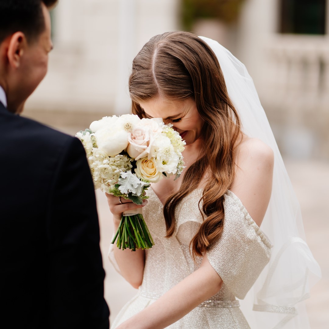 Bride laughing during the vows,
                              hiding her face behind her bouquet